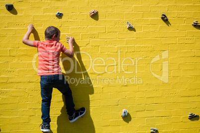 Rear view of boy climbing on yellow wall