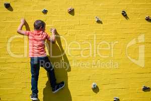 Rear view of boy climbing on yellow wall