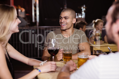 Happy young man with friends sitting at nightclub