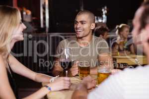 Happy young man with friends sitting at nightclub