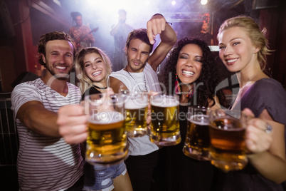 Portrait of happy friends holding beer mugs at nightclub