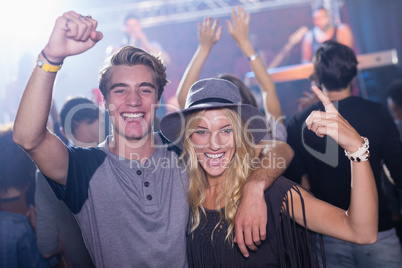 Portrait of cheerful friends with arm around at nightclub