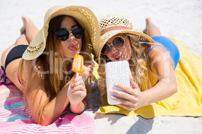 Female friends talking selfie while having popsicles