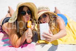 Female friends talking selfie while having popsicles