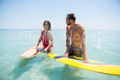 Couple with surfboard standing in sea