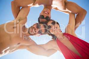 Directly below shot of smiling young friends huddling against clear blue sky