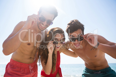 Low angle portrait happy of friends wearing sunglasses against clear sky