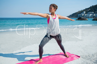 Full length of young woman exercising at beach