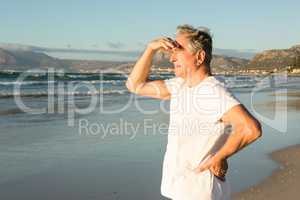 Senior man looking away while standing on shore