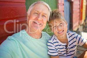 Portrait of smiling boy with grandfather sitting by wall