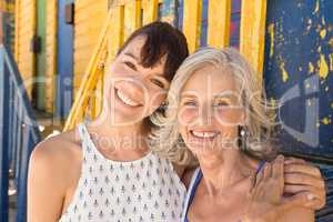 Portrait of smiling mother and daughter standing against wall