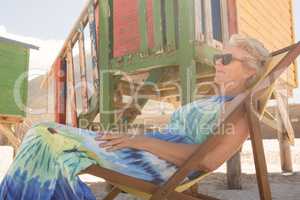 Close up of smiling senior woman with sunglasses resting on chair