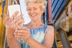 Close up of happy senior woman listening music on smart phone