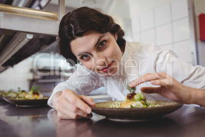 Female chef examining appetizer plate at order station