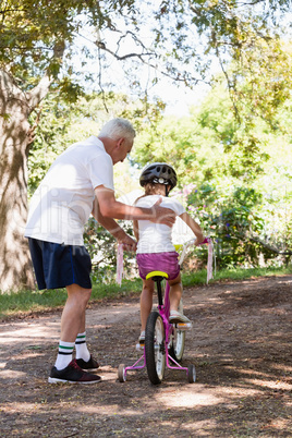 Grandfather teaching his granddaughter how to ride a bicycle