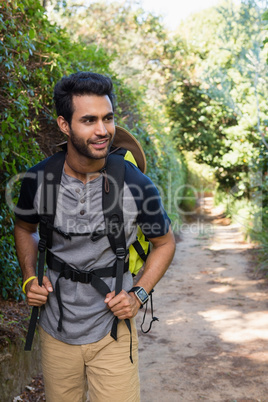 Smiling man with backpack walking in the forest