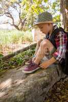 Boy tying shoelace in the forest