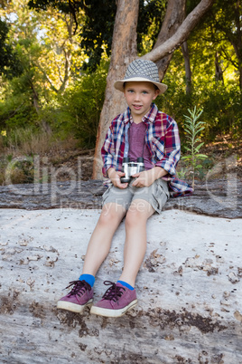 Boy sitting on the fallen tree trunk in the forest