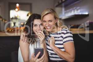 Portrait of happy friends using mobile phone