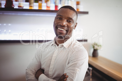 Man standing with arms crossed in restaurant