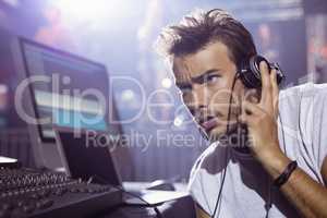 Thoughtful male dj with headphones at nightclub