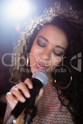 Female singer with eyes closed performing at nightclub