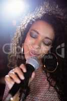 Female singer with eyes closed performing at nightclub