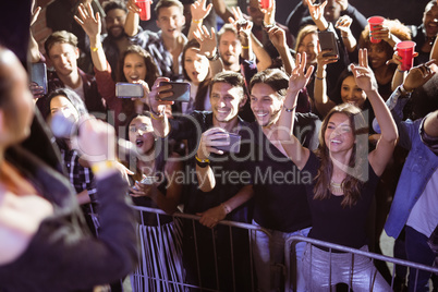 Cheerful young fans photographing performer at nightclub