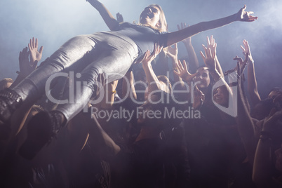 Cheerful fans lifting female performer at nightclub