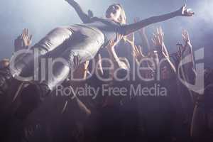 Cheerful fans lifting female performer at nightclub