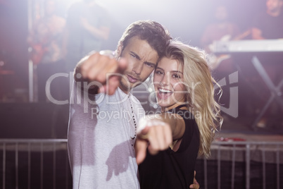 Portrait of smiling couple pointing at nightclub