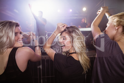 Happy female friends dancing at nightclub