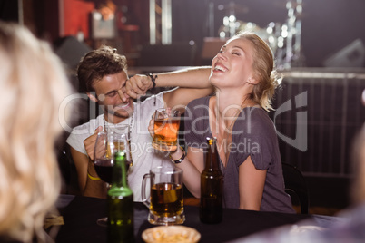 Cheerful friends holding beer mugs at nightclub