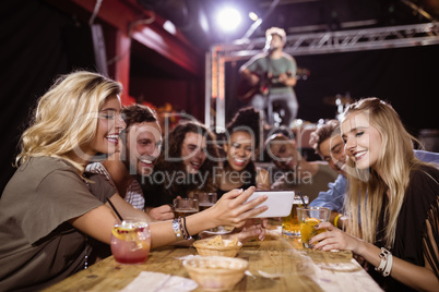 Woman showing smart phone to friends while sitting at table