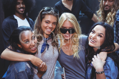 Portrait of happy women with male friends in background