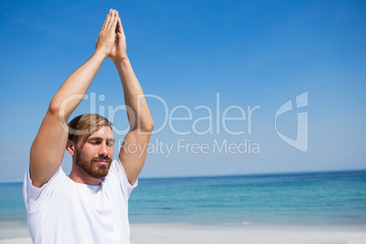 Man with hands clasped exercising at beach