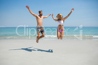 Playful couple jumping at beach