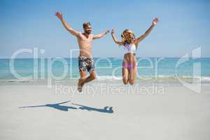 Playful couple jumping at beach