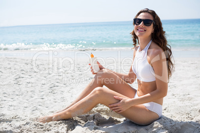 Portrait of woman wearing sunglasses while applying sunscream