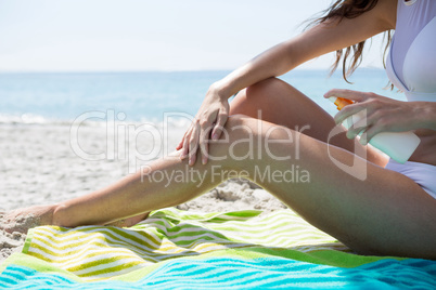 Low section of woman applying sunscream on legs