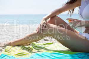 Low section of woman applying sunscream on legs