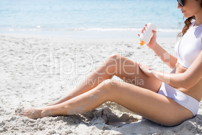 Side view of woman applying sunscream on legs