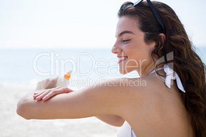 Side view of woman applying sunscream on arms