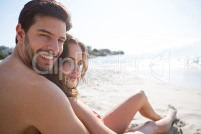 Portrait of young shirtless man with his girlfriend sitting at beach