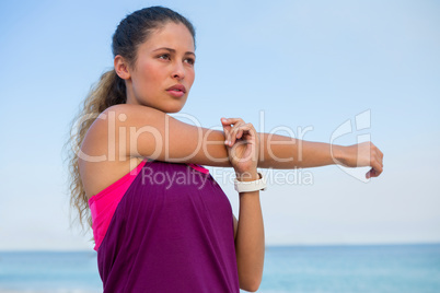 Thoughtful young woman stretching at beach