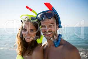 Portrait of happy young couple wearing scuba masks together at beach