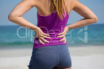 Mid section of woman standing with hands on hip at beach