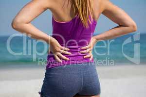 Mid section of woman standing with hands on hip at beach