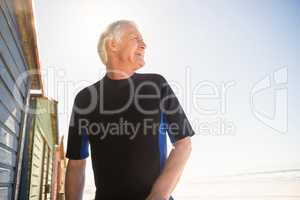 Happy senior man looking away while standing by beach hut