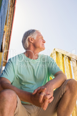 Senior man looking away while sitting at hut